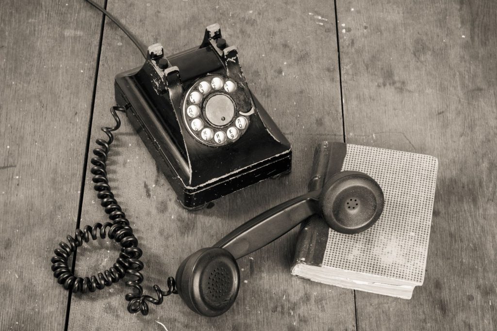 17627846 - vintage telephone, book on old table grunge background